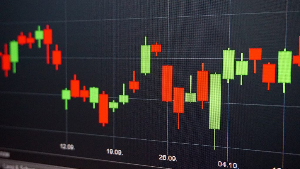 Close-up of red and green candlestick stock chart on a dark trading screen. 
